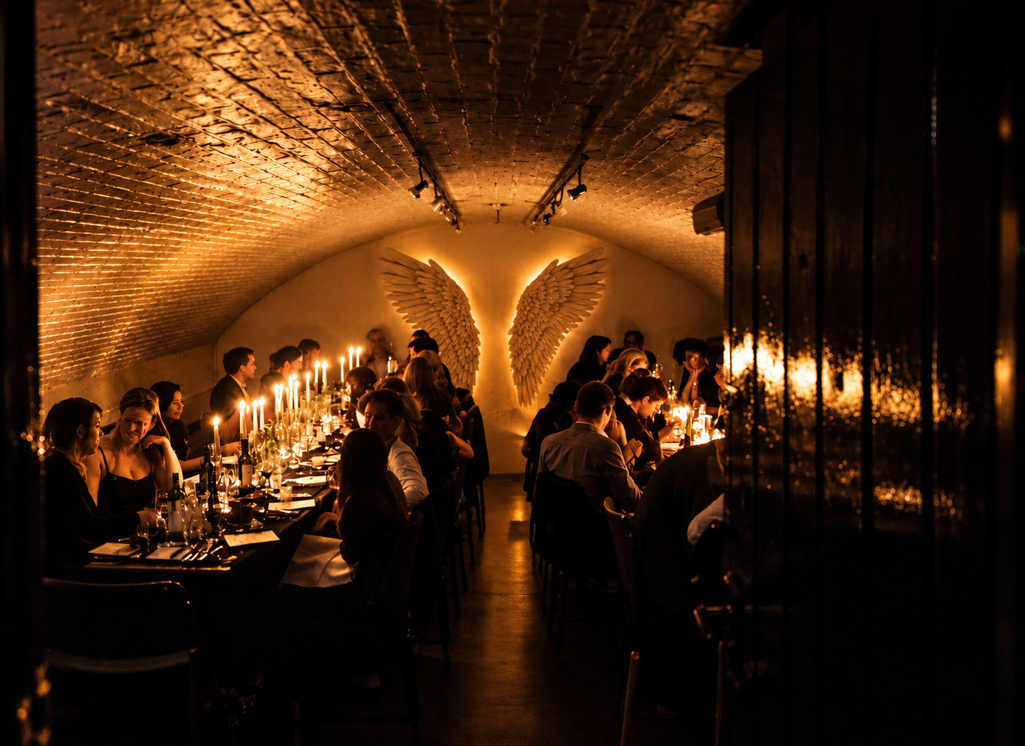 Candlelit dinner beneath illuminated angel wings